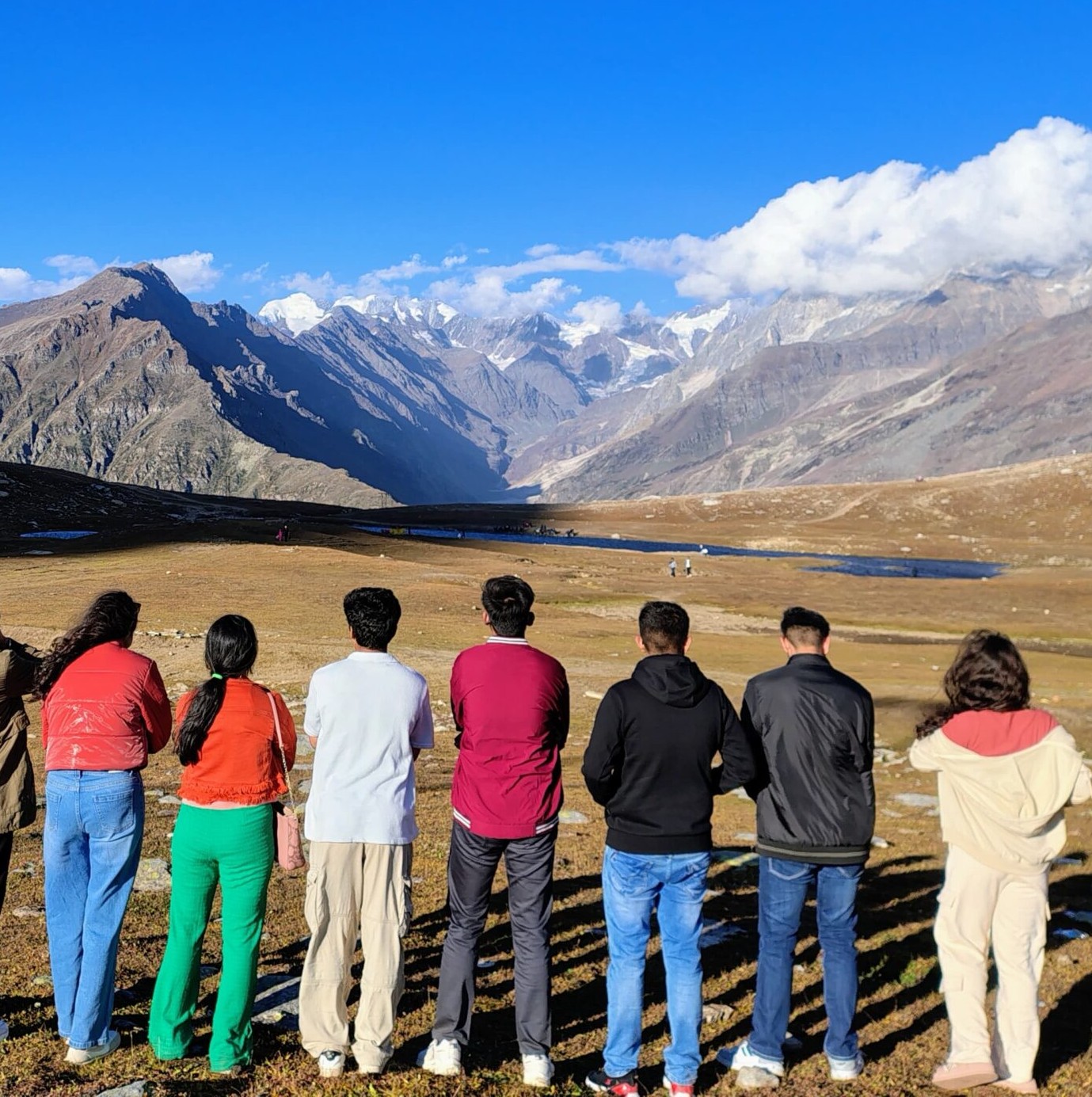A large group of friends seen from back in front of mountains.
